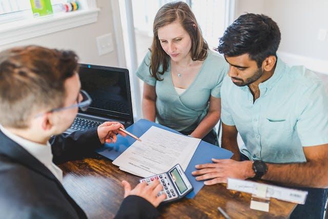 Expert realtor in a real-estate office giving financial guidance to a family seeking a new home or property. Using calculator to get rent or property price correct. The office of Edmonton Real estate Experts and Trusted Advisers Realty Canada - Real Estate Organisation