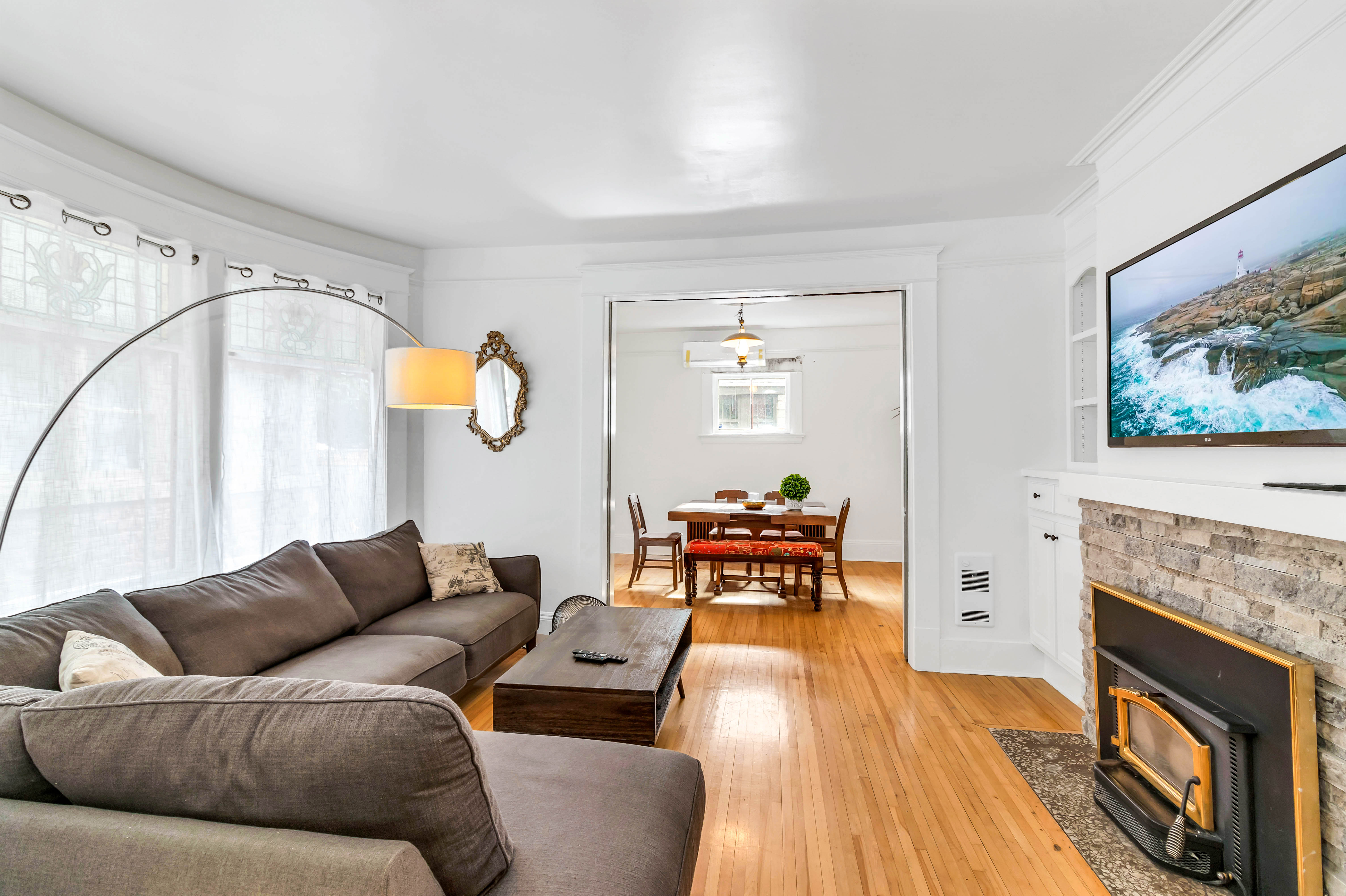 View from the second living room into the dining area, featuring hardwood floors and natural light from multiple windows.