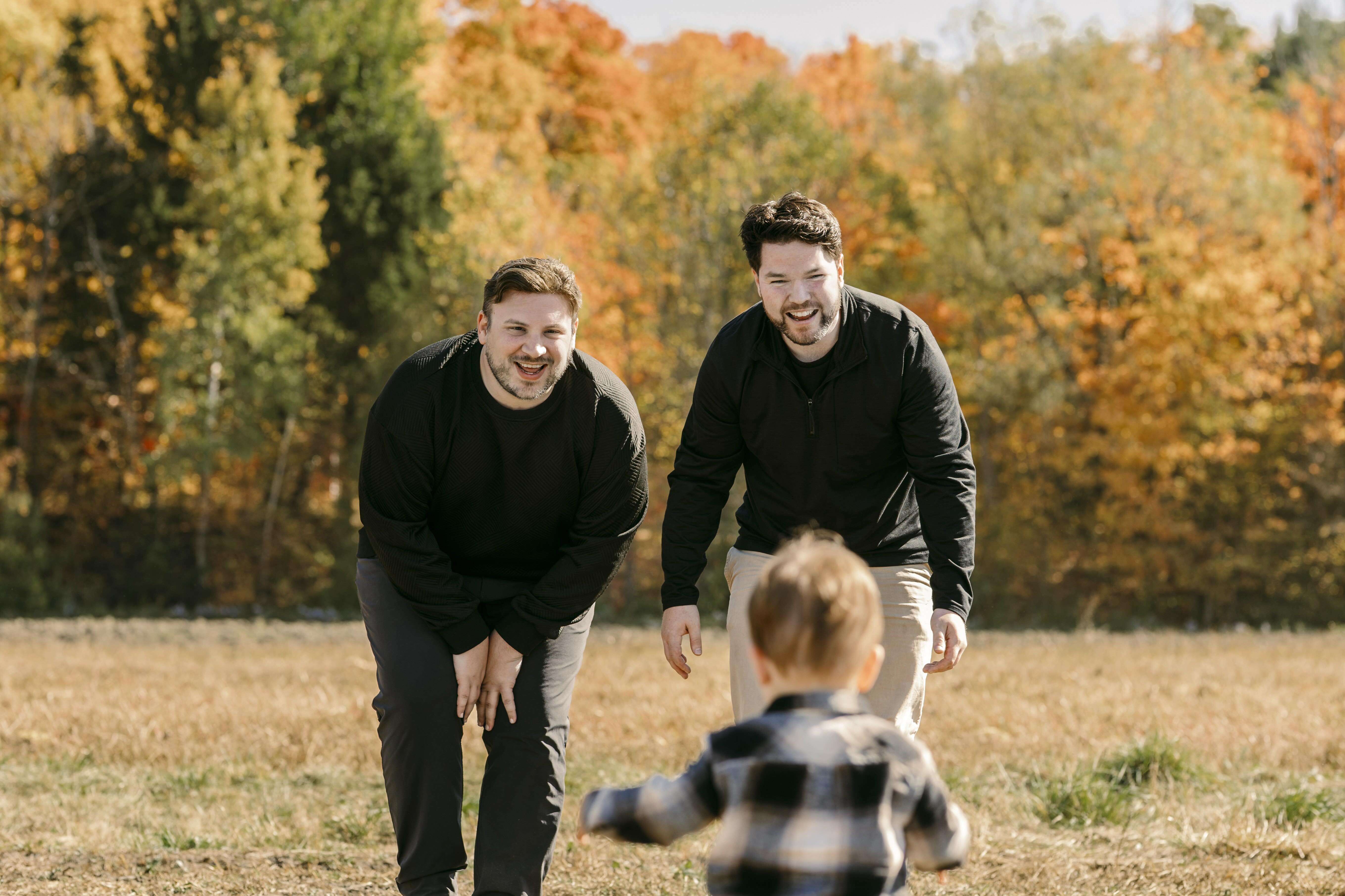 Kyle Dawson and his husband Brandon playing with their son in a field near Ottawa.